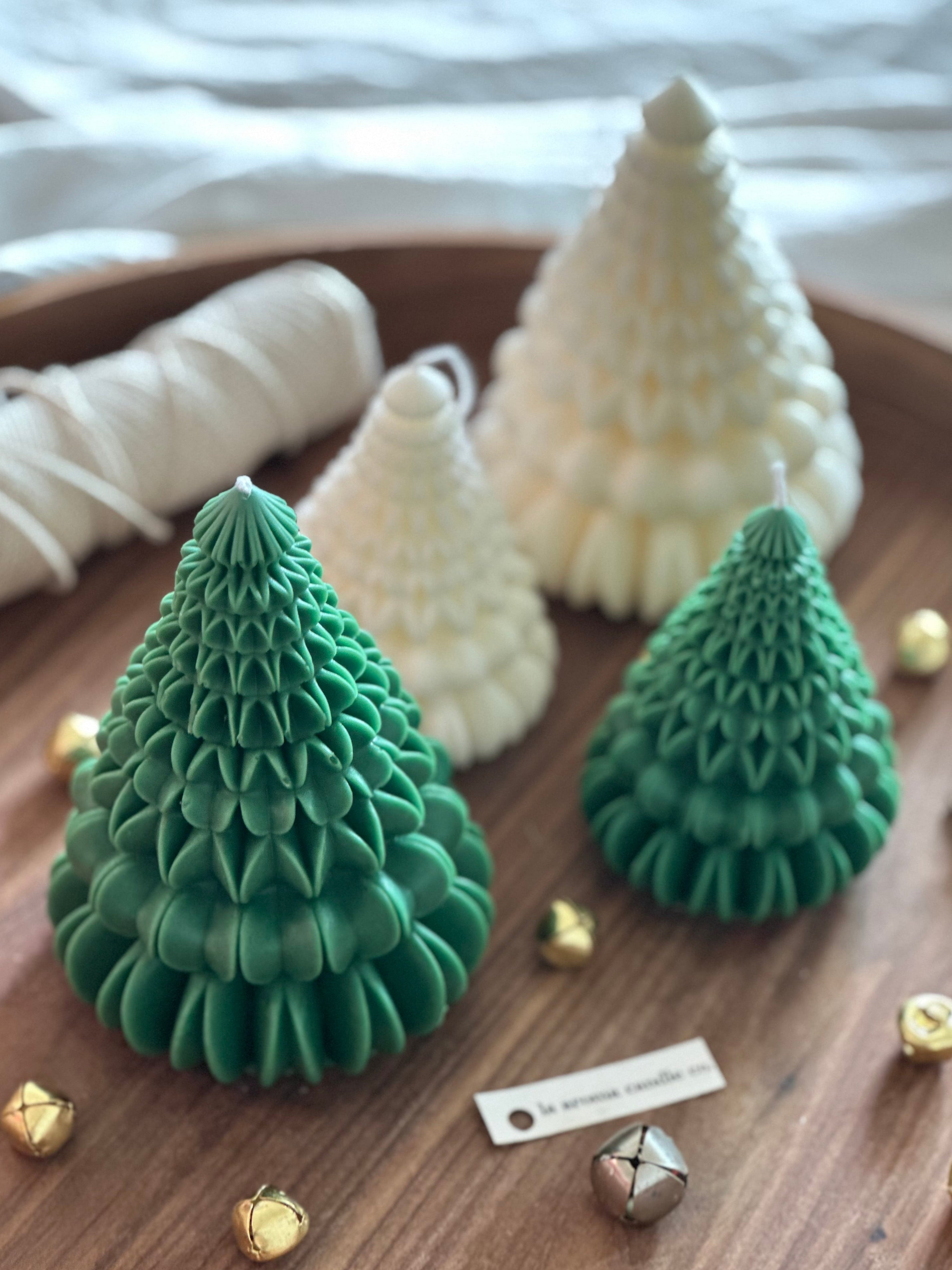 Three green and white textured candle trees on a wooden surface with decorative elements.